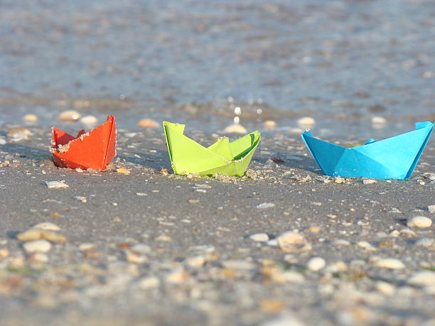 istock Blue, green and red paper boats are  on a beach 485320708