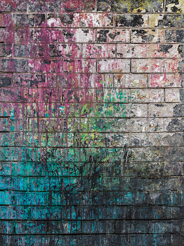 Dirty brick wall painted with spots of paint colors.