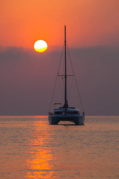 Sailing catamaran on background of a beautiful sunset in sea stock photo