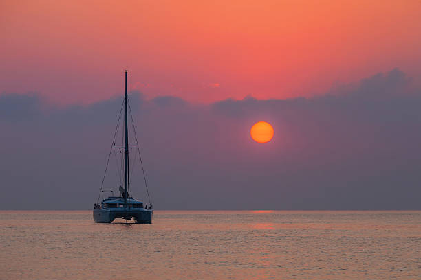 Sailing catamaran on background of a beautiful sunset in sea stock photo