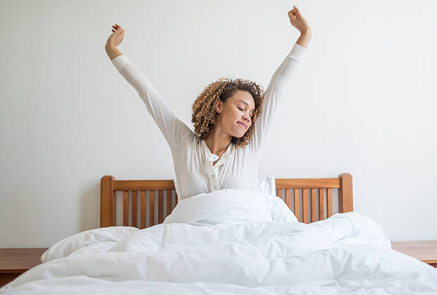 mujer bostezar en la cama - despertar fotografías e imágenes de stock