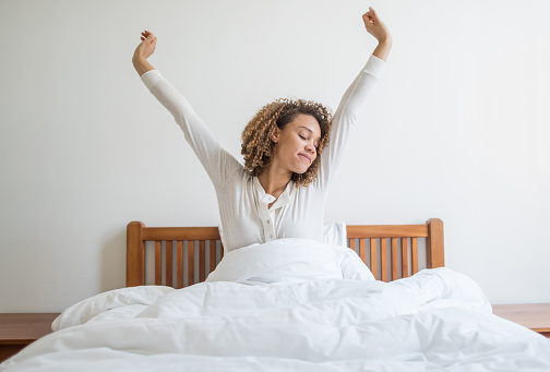 Happy woman yawning in bed waking up in the morning