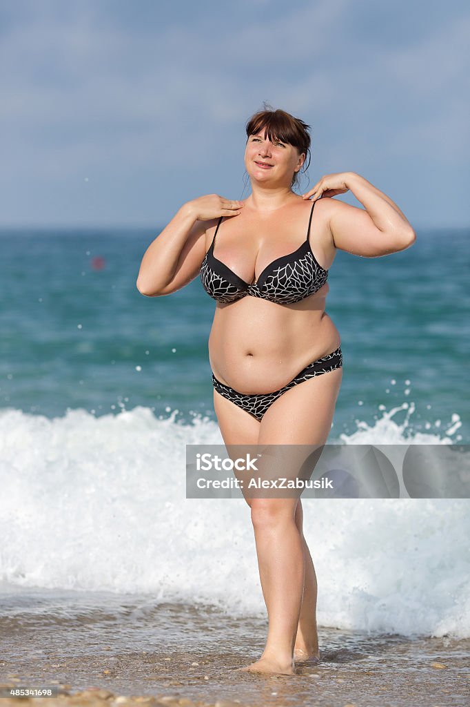 Overweight young woman at the sea Woman in swimwear at the sea. Overweight young woman in swimsuit posing against the sea Overweight Stock Photo