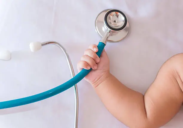 Photo of medical instruments stethoscope in hand of newborn baby girl