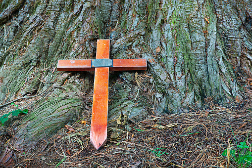 Image of a wooden crucifix lying against a tree