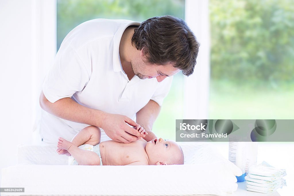 Jovem pai a falar para recém- nascidos relaxante na mudança de tabela - Royalty-free Fralda Foto de stock