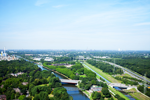 Aerial view of Rhine-Herne-Canal and western Ruhrgebiet with plants in Duisburg at horizon. Summer shot from Gasometer Oberhausen.