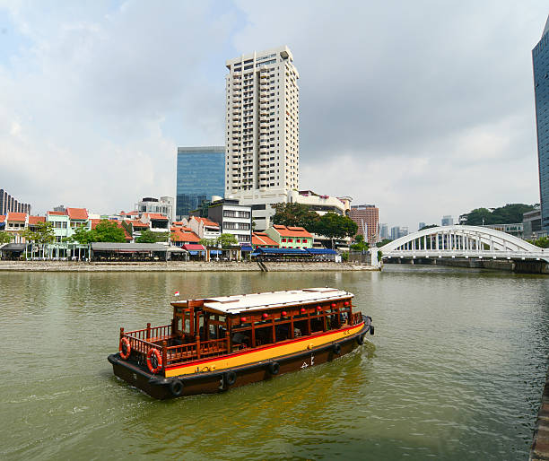 Singapore, Singapore - July 3, 2015: View of tourist boat floating on Singapore river with downtown buildings in the background.