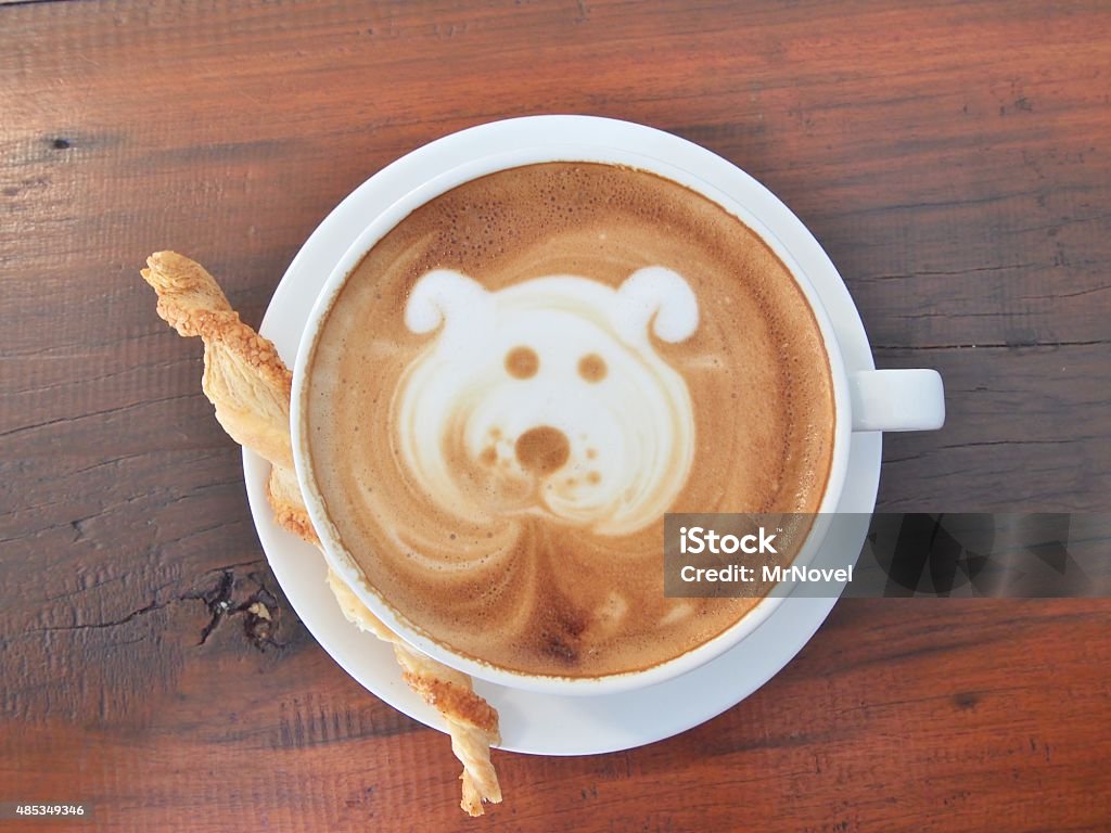 Latte Coffee art and biscuit stick on the wooden desk. Latte Coffee art "Dog Face" and biscuit stick on the wooden desk. Coffee - Drink Stock Photo