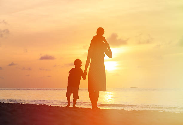 istock mother with two kids walking on sunset beach 485349486
