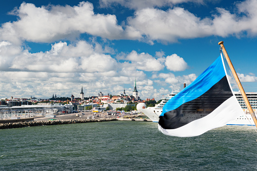 Tallinn, Estonia - August 13, 2015: Harbour of Tallinn. Estonia flag blowing in wind also old town in background.