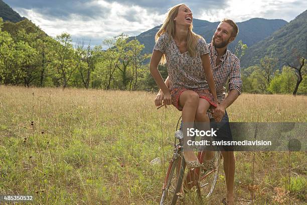 Young Couple Riding On A Vintage Bicycle In The Countryside Stock Photo - Download Image Now