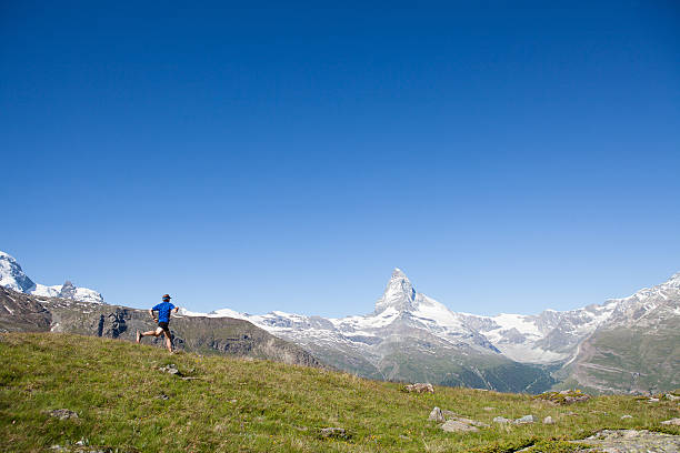Young interracial couple laughing and running on a mountain road, enjoying a healthy lifestyle