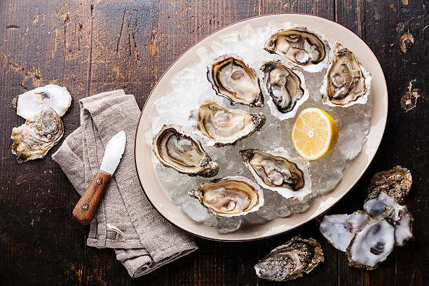 istock Opened Oysters on plate with ice and lemon 485350828