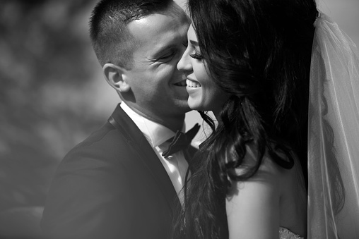black and white shot of bride and groom smiling, kissing and being romantic.affectionate feelings.