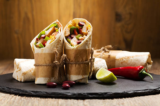 Burritos wraps with chicken Burritos wraps with chicken, beans and vegetables on wood board mexican culture food mexican cuisine fajita stock pictures, royalty-free photos & images