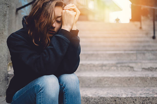 triste chica sesión cuidadosamente en la calle - sin esperanza fotografías e imágenes de stock