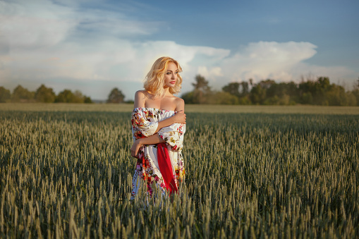 Beautiful girl in a field at sunset. She bared shoulders.