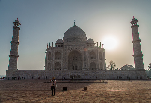 Agra, India - February 28, 2015: Backlit view of Taj Mahal from West side with tourist taking selfie.