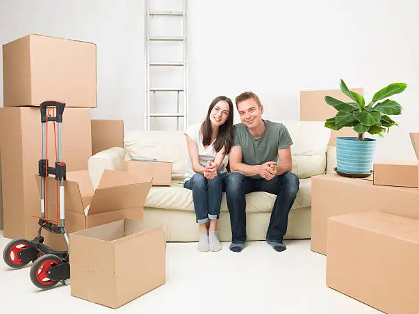 happy couple sitting on sofa after moving in new house