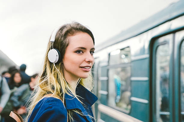 красивая женщина, слушать музыку на свой смартфон, поезд метро фоне - rush hour audio стоковые фото и изображения