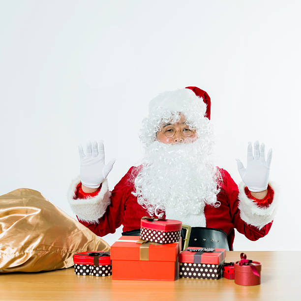 Santa claus with group of gifts on desk.