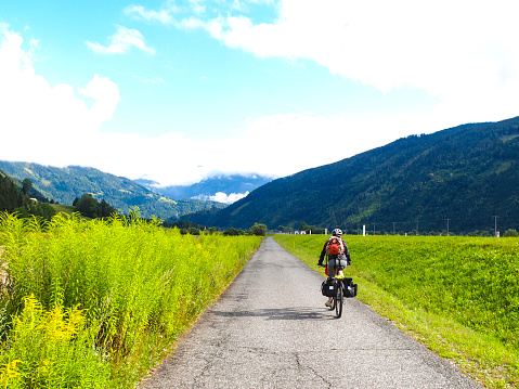 Front view of Biker riding on Drau cycle path near Dellach, Austria. It is located in Valley of the Drava River and is one of nicest world Drau bike cycle paths ( Drauradweg R1). It goes from Toblach trough Innichen in Italy, Spittal, and Villach in Austria and to Maribor in Slovenia. It is grey cloudy day...