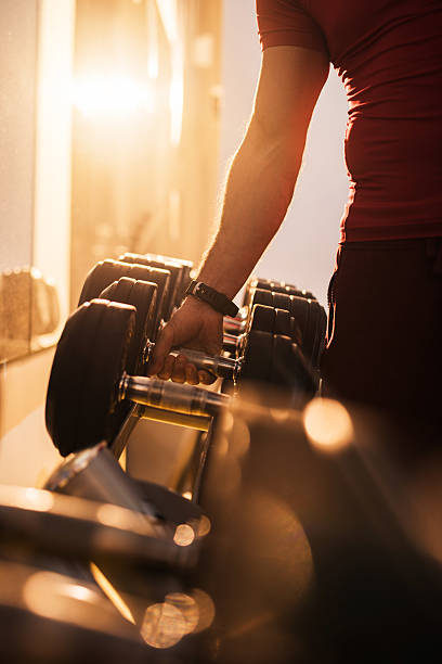 Unrecognizable man taking dumbbell from a rack at gym.