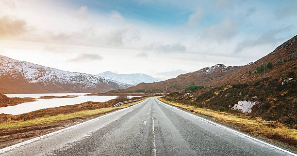 Panoramic Highway to Isle of Skye, Highlands Scotland Endless highway through snow covered scotish mountains towards the Isle of Skye under an amazing sunny winter sky. North-West Highlands of Scotland, United Kingdom. lochaber stock pictures, royalty-free photos & images