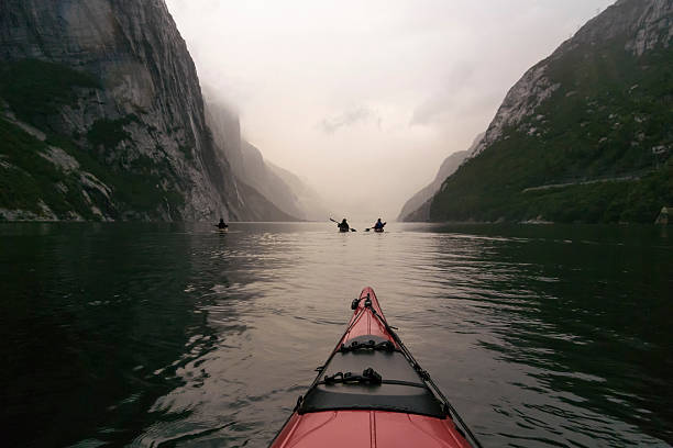 Kayaking in a Fjord in Norway during twilight View from a red kayak in the Lysefjord in Norway during twilight at the end of a cloudy and misty day. Lysefjord or Lysefjorden is a fjord located in Forsand in Ryfylke in south-western Norway east of the city of Stavanger. It is a popular fjord to visit for tourists and famous for the rock of Preikestolen and the Kjeragbolten. lysefjorden stock pictures, royalty-free photos & images