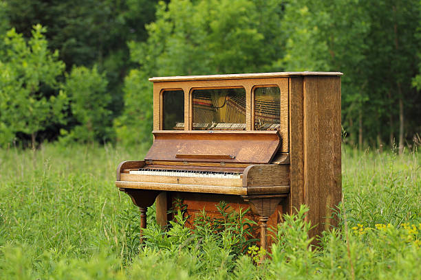 istock Old Upright Piano Seen Abandoned in a Green Field 485373087