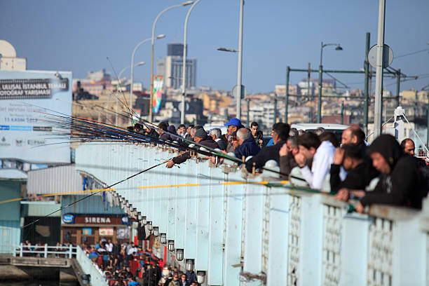 Istanbul, Turkey - April 8th, 2014: Crowded Galata bridge is full of fishermen catching fishes for lunch, dinner and also for sale. For some of them is a bridge fishing a way of living.