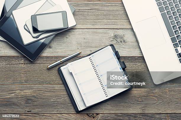 Stack Of Mobile Devices And Laptop On A Wooden Table Stock Photo - Download Image Now