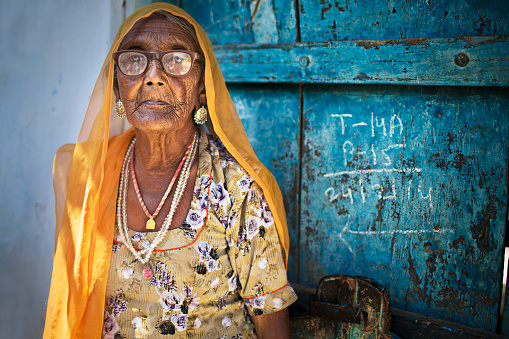 Portrait of an Indian senior woman in front of a blue door .