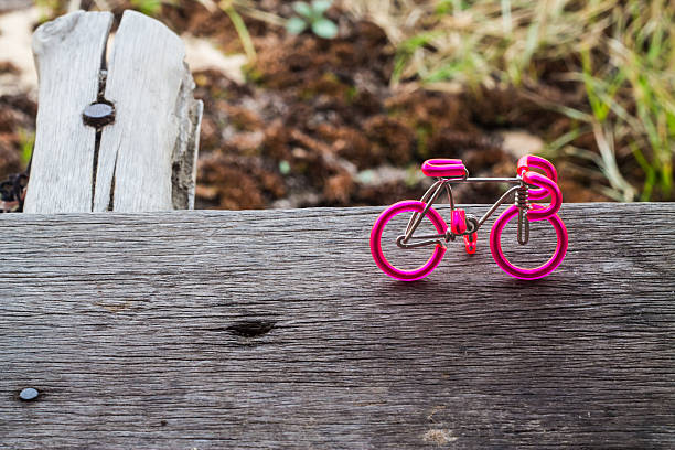Wire rod pink bike lay on the wooden floor.