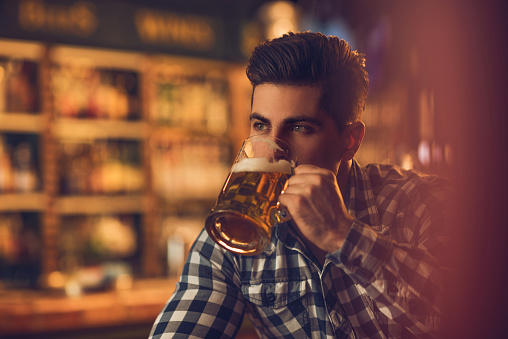 Young pensive man drinking beer in a pub.