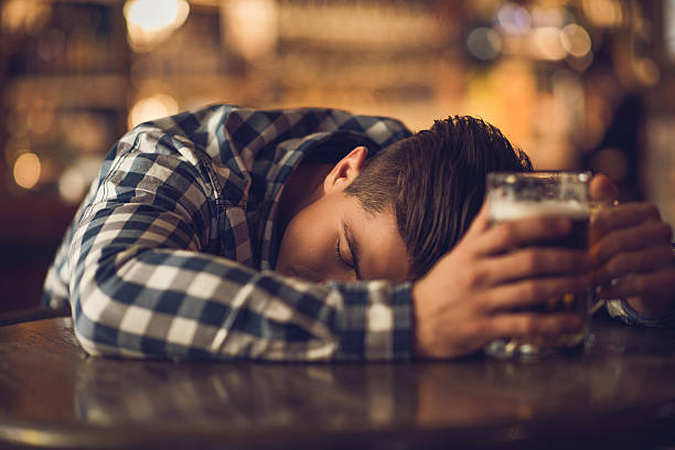 若い酔っ払いマンベッドルームには、テーブル、バーがございます。 - alcoholism drunk addiction drinking ストックフォトと画像