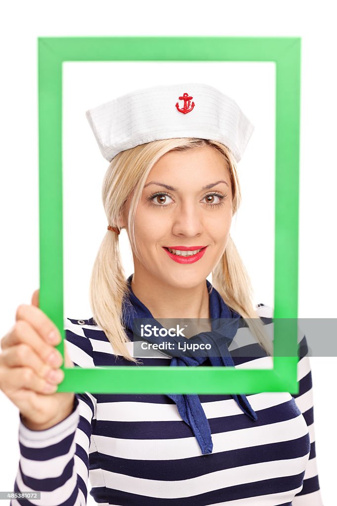 Young female sailor holding a green picture frame Vertical shot of a young female sailor holding a green picture frame and looking at the camera isolated on white background 20-29 Years Stock Photo