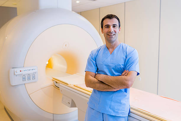 sonriendo confianza radiólogo y un escáner de mri. - mri scan radiologist cat scan cat scan machine fotografías e imágenes de stock