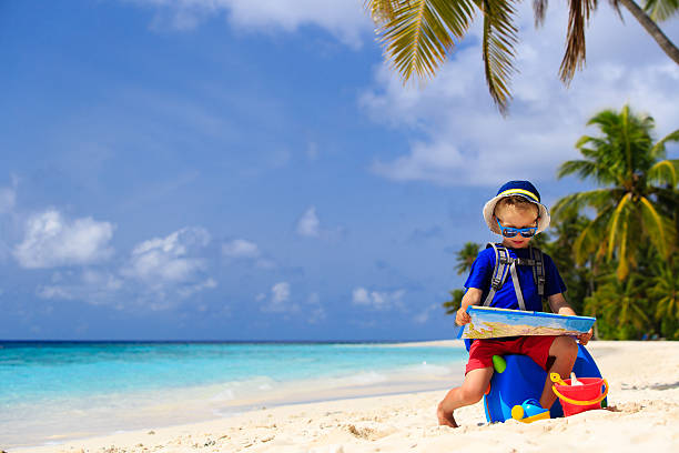istock little boy travel on summer tropical beach with suitcase 485382590