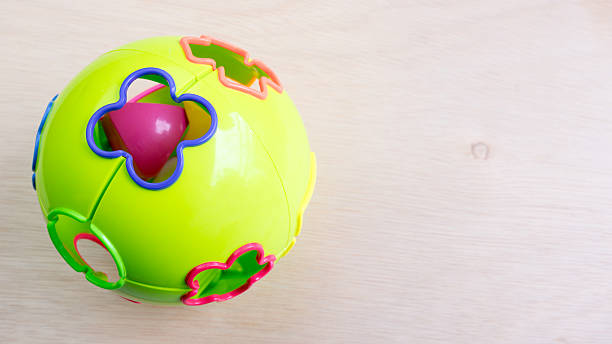 istock Green colour plastic ball with shape holes on wooden surface 485383104