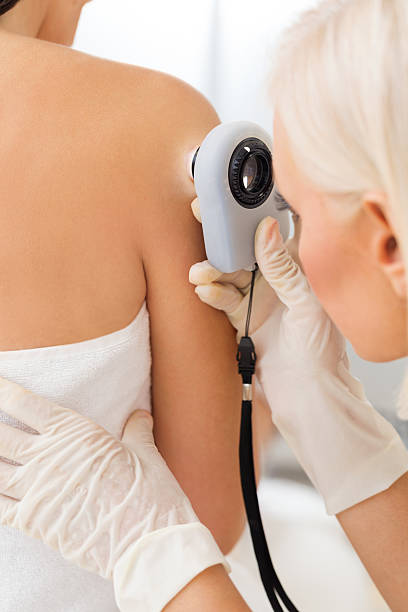 Dermatologist checking for skin cancer Female dermatologist examining female patient's skin with dermascope, doctor is carefully looking for signs of skin cancer skin exame stock pictures, royalty-free photos & images