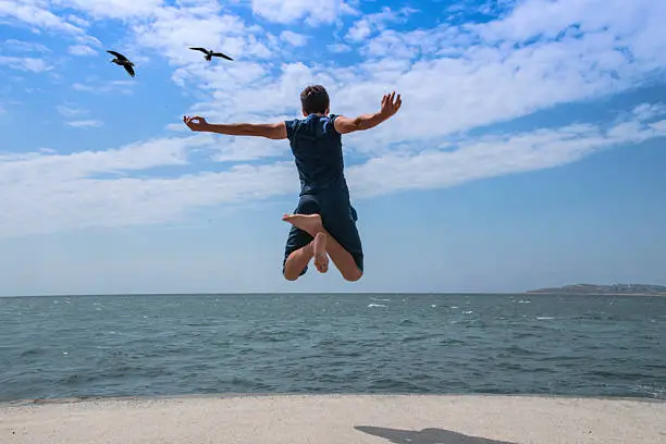 young man jumping in the air to the sea.