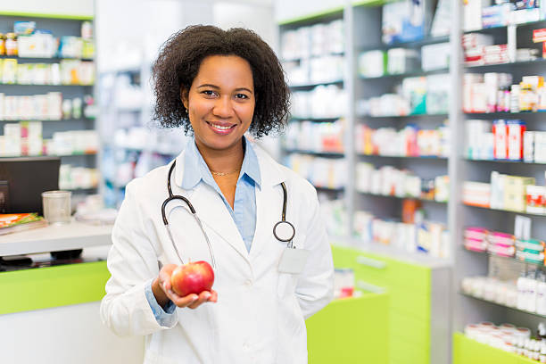 istock African American pharmacist holding apple and looking at camera. 485393508