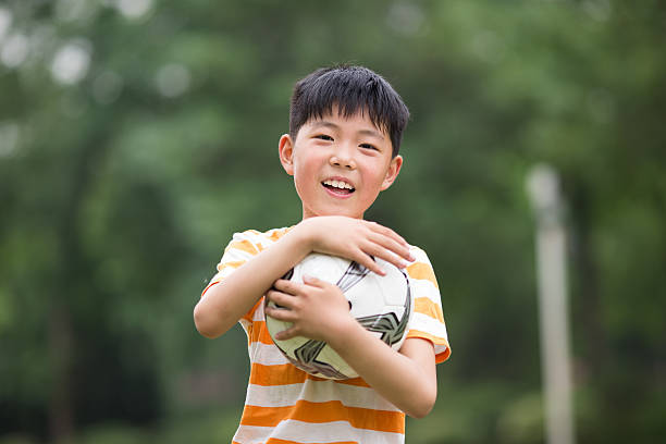 istock boy playing football at park 485393992