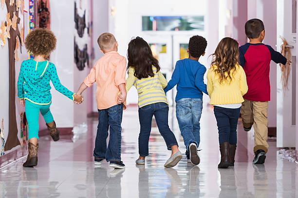 vue de dos, groupe de preschoolers marchant le long couloir - back school photos et images de collection