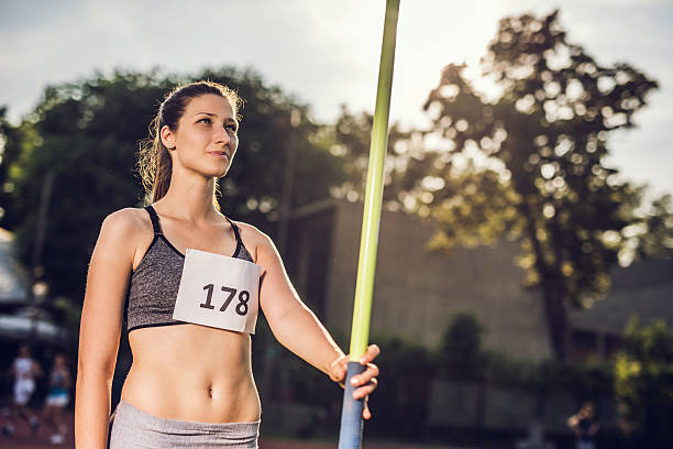 улыбается спортивный женщина, подготовка к выполните javelin. - javelin sport photography outdoors стоковые фото и изображения