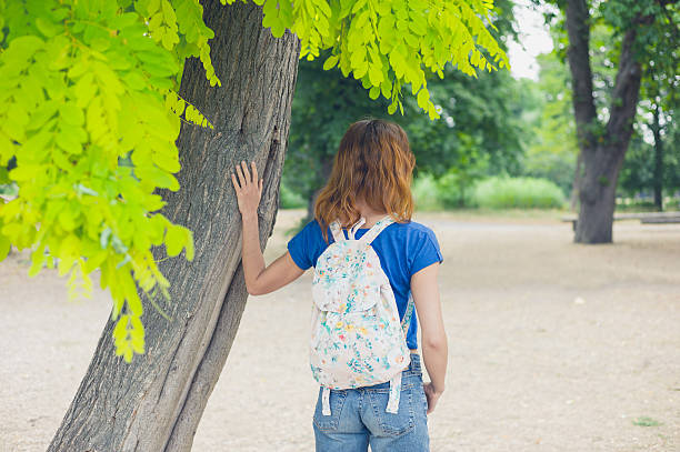 istock Young woman standing uinder a tree in the park 485402654