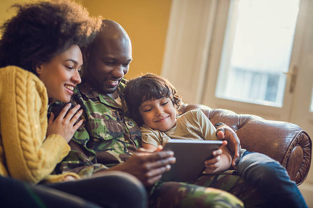 istock Happy military family relaxing at home and using digital tablet. 485403058
