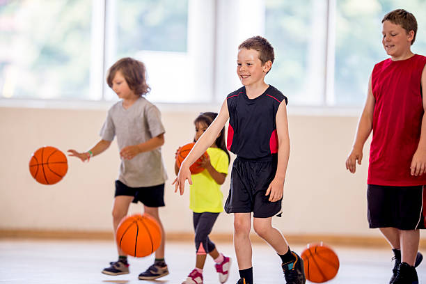 kinder einen basketball dribbeln - volleyball sport floor ball stock-fotos und bilder